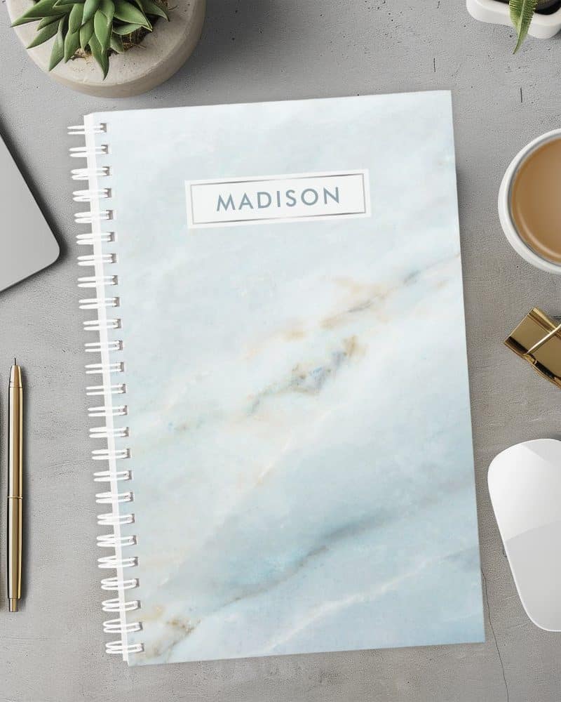 Spiral-bound notebook with a light blue marble design and the name Madison on the cover.