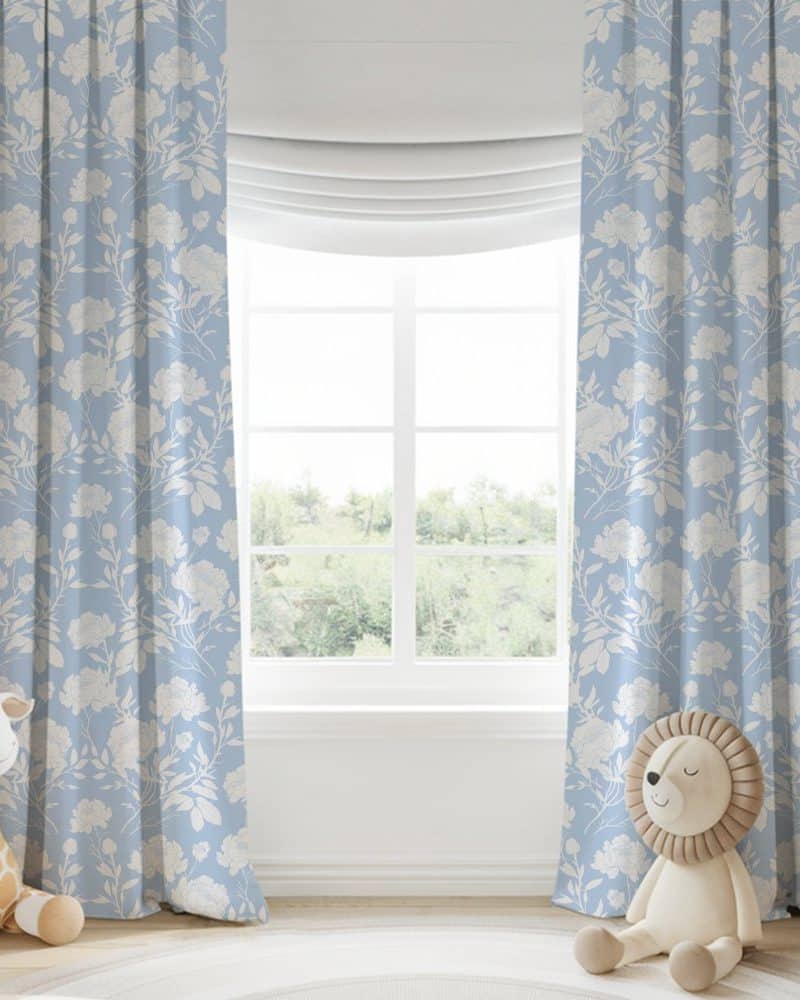 Light blue curtains with a white floral pattern hang on a window.