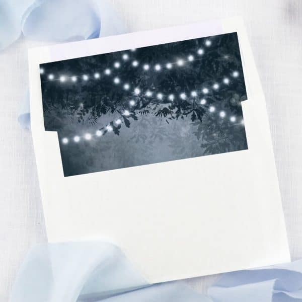 White Envelope With A Dark Blue Liner Featuring String Lights In Trees.