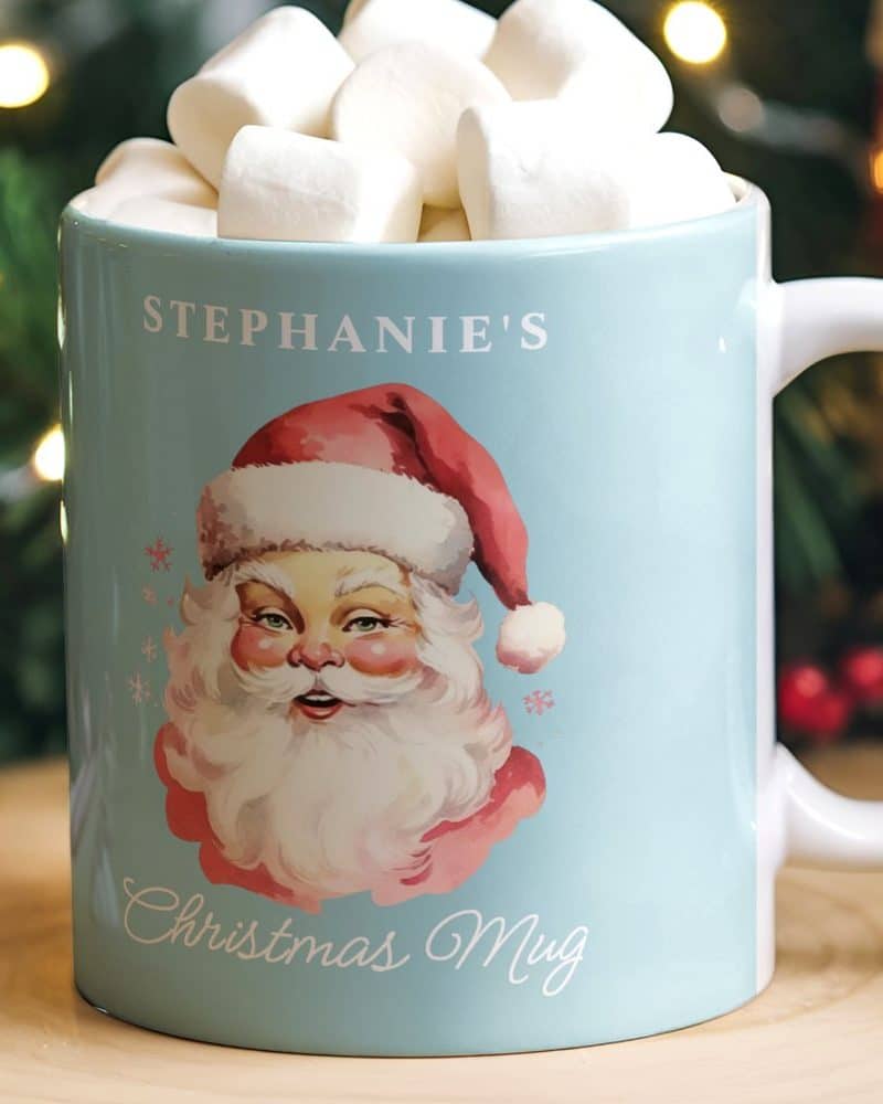 Light blue mug with Santa Claus illustration and personalized name, filled with marshmallows.