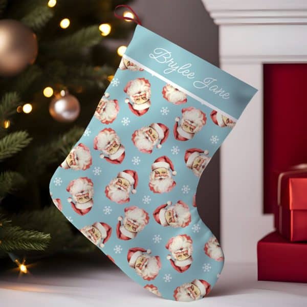 Personalized Christmas Stocking With A Light Blue Background And A Repeating Pattern Of Santa Claus Faces. The Stocking Is Labeled Brylee Jane.