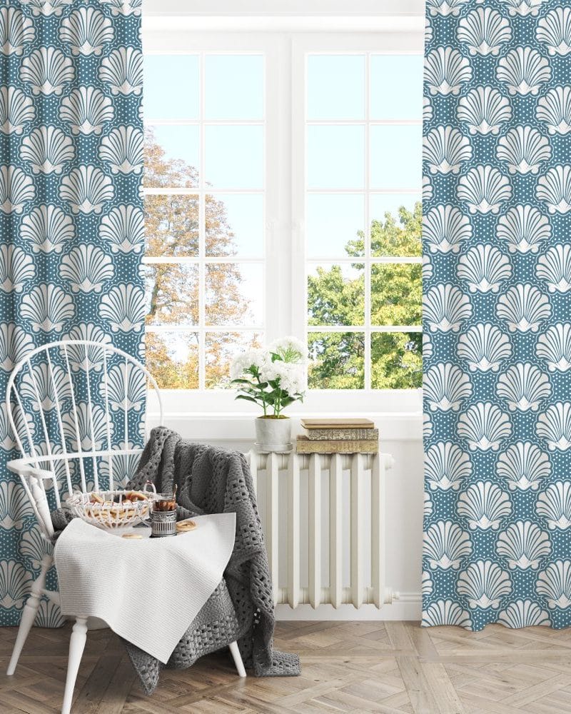 A pair of teal curtains with a white seashell pattern hangs in a window.