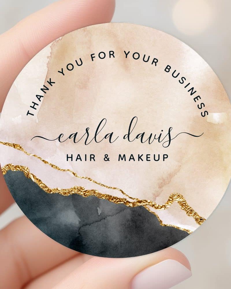 Round thank you sticker with a watercolor design in beige, black, and gold, featuring the name Carla Davis Hair & Makeup.