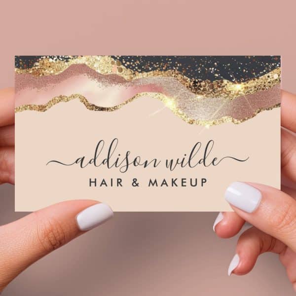 A Business Card For Addison Wilde Hair &Amp; Makeup. The Card Features A Design Of Rose Gold And Black Glitter Accents.