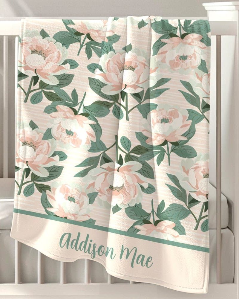 Personalized baby blanket with a peach and green floral pattern and the name Addison Mae.