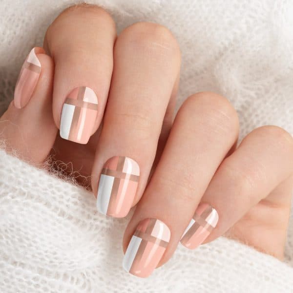 Close-Up Of A Hand With Nails Painted In A Peach And White Plaid Design.