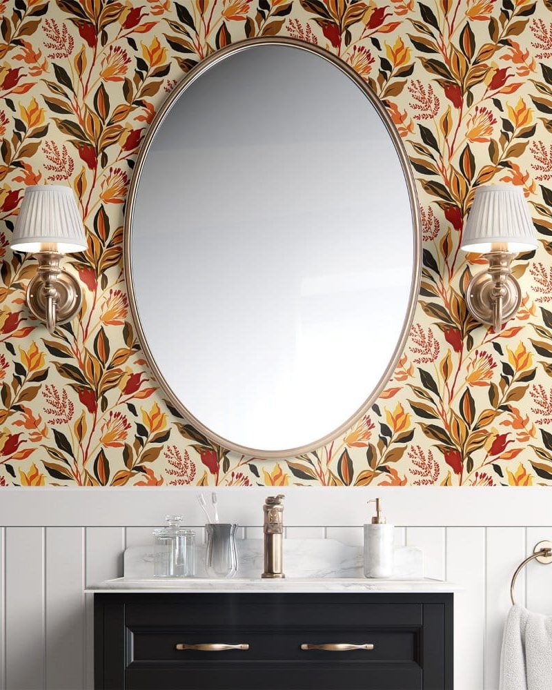 Oval mirror above a bathroom vanity with autumnal floral wallpaper.