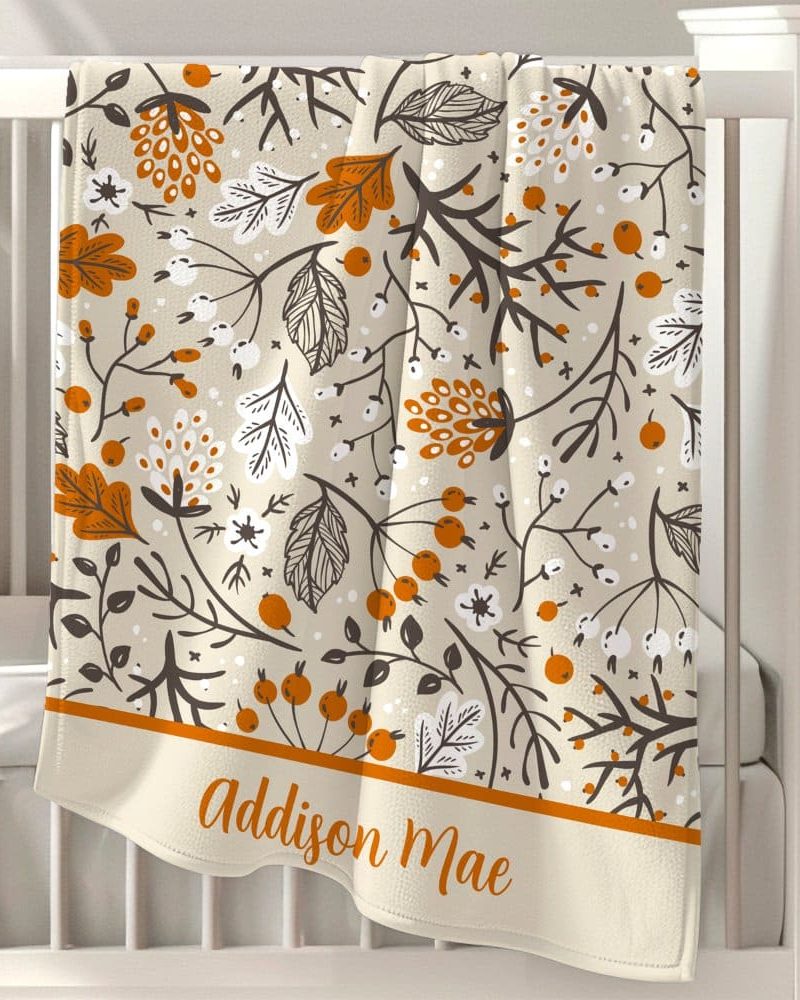 Beige baby blanket with an orange and brown floral pattern and the name Addison Mae at the bottom.
