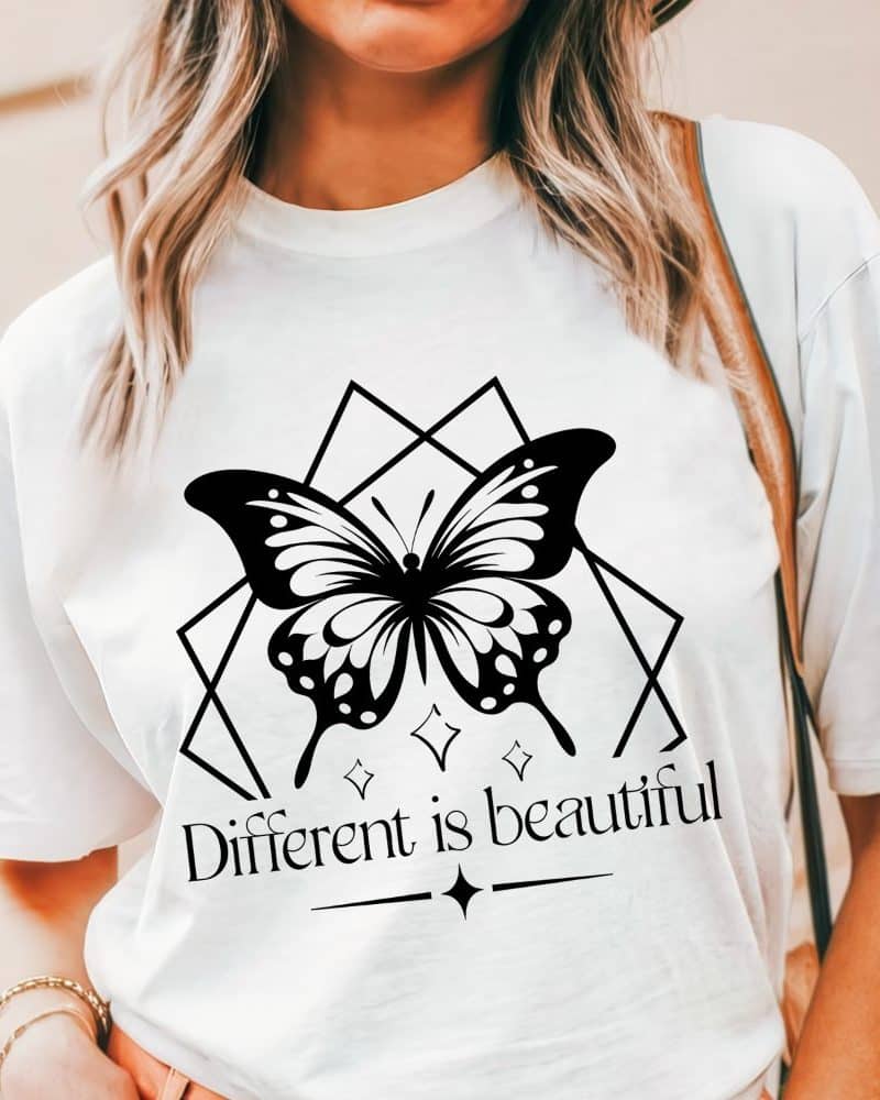 White t-shirt featuring a black butterfly graphic within a geometric design, and the text Different is beautiful.