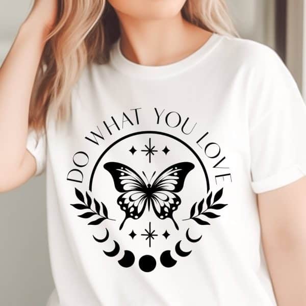 White T-Shirt With A Black Graphic Design Featuring A Butterfly, Crescent Moons, Stars, And The Text Do What You Love.