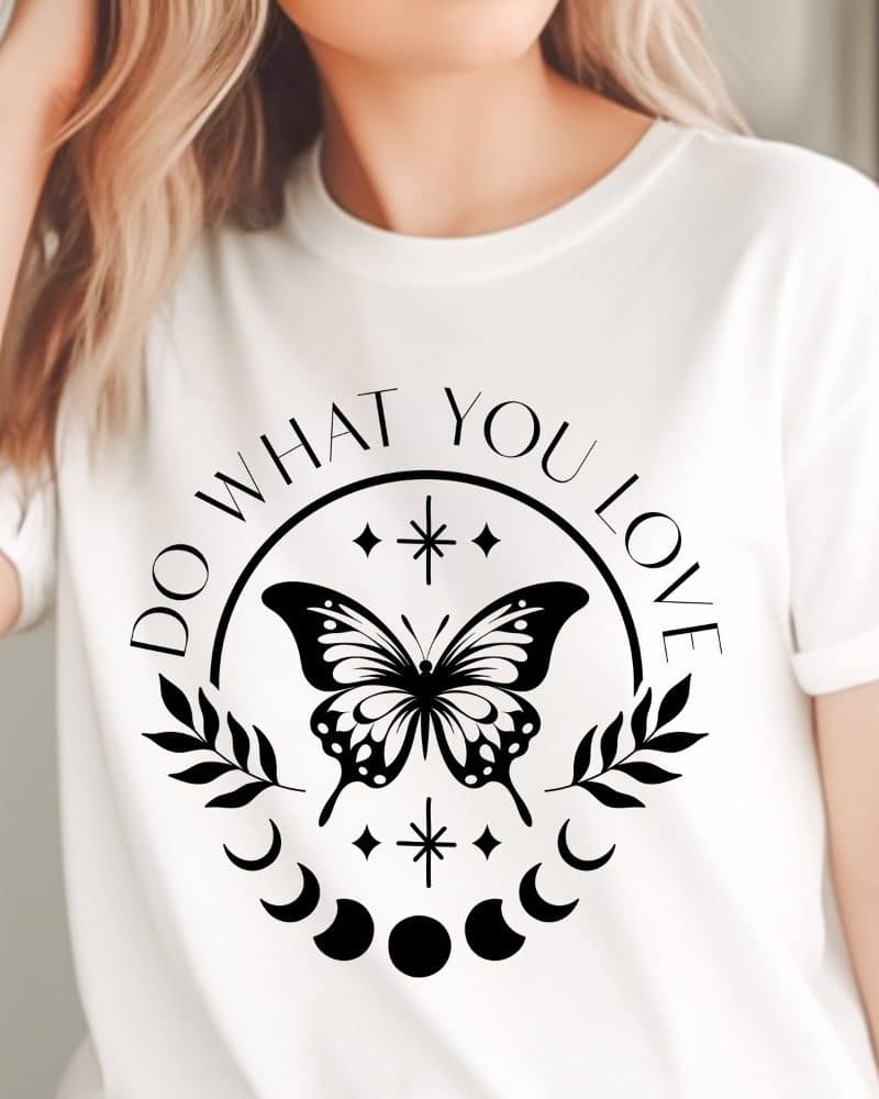 White t-shirt with a black graphic design featuring a butterfly, crescent moons, stars, and the text Do What You Love.