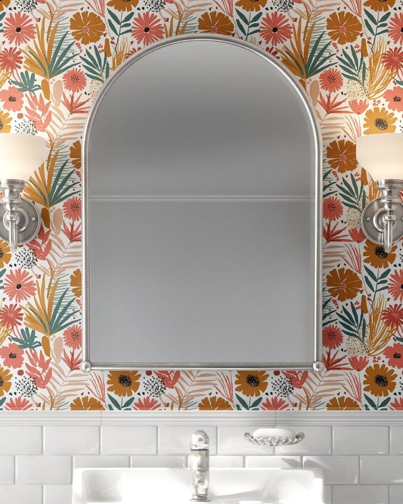 Arch-shaped mirror in a bathroom with floral wallpaper.