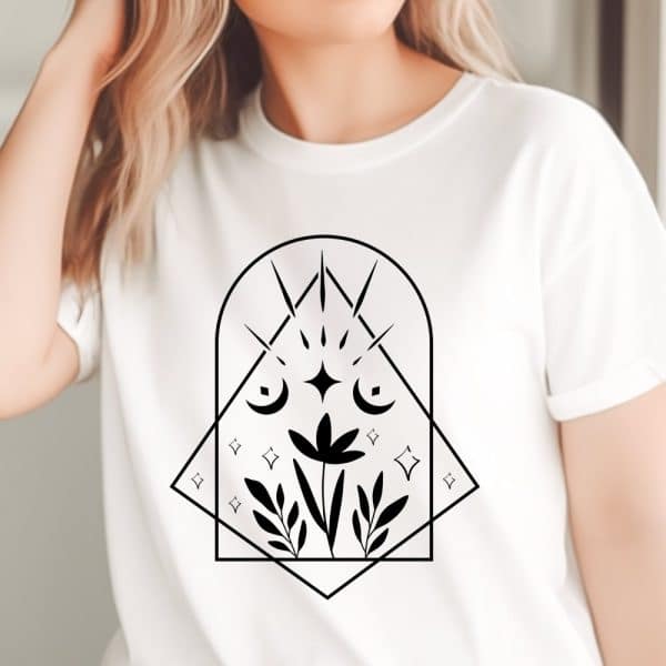 White T-Shirt With A Black Geometric Design Featuring A Flower, Crescent Moons, And Stars.
