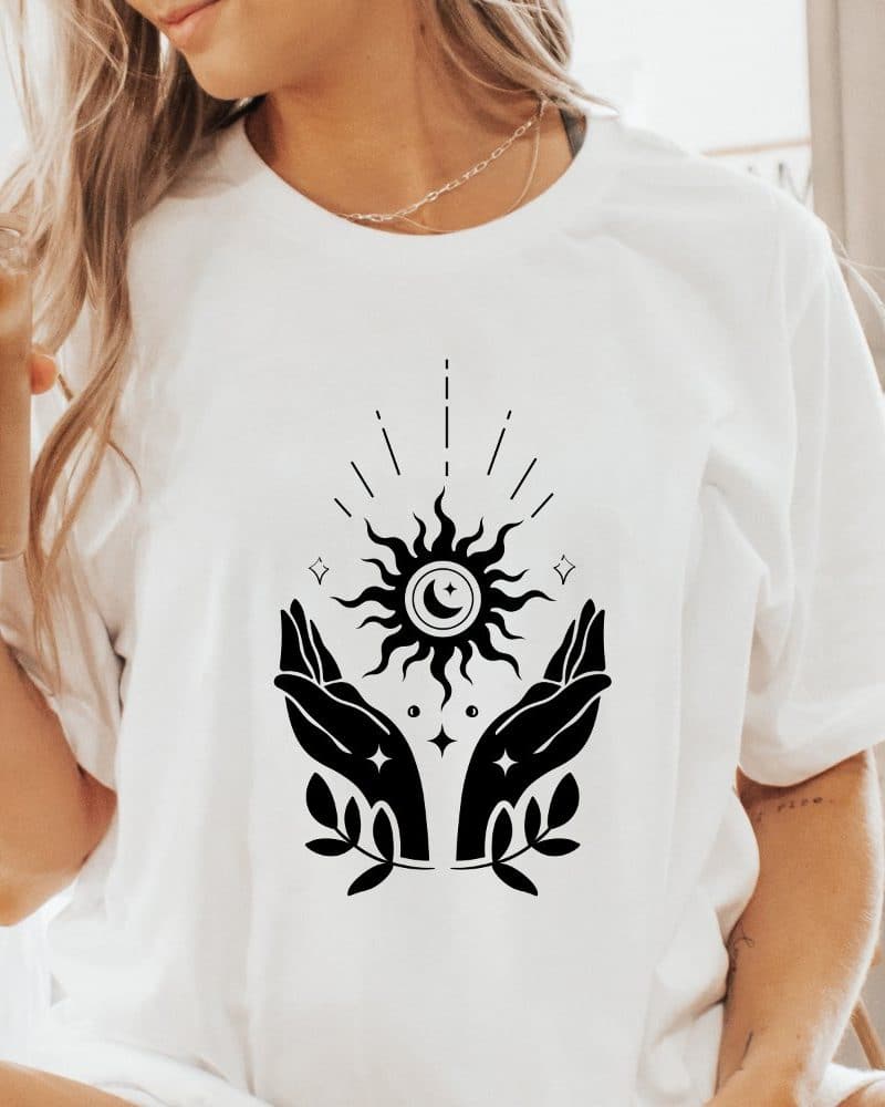 White t-shirt with a black design of two hands cradling a sun and moon.