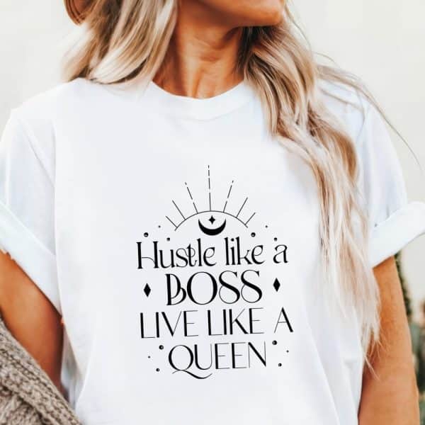 White T-Shirt With The Text Hustle Like A Boss Live Like A Queen. A Crescent Moon And Sunburst Graphic Is Above The Text.
