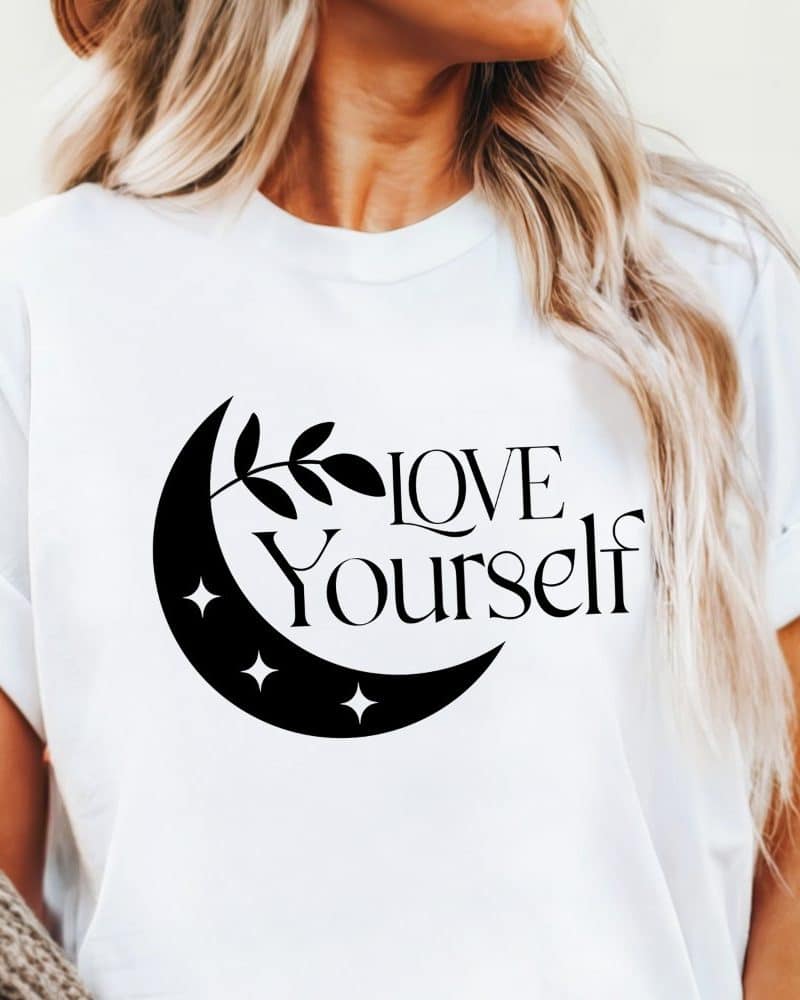 White t-shirt with a black crescent moon, leaves, and the words Love Yourself.