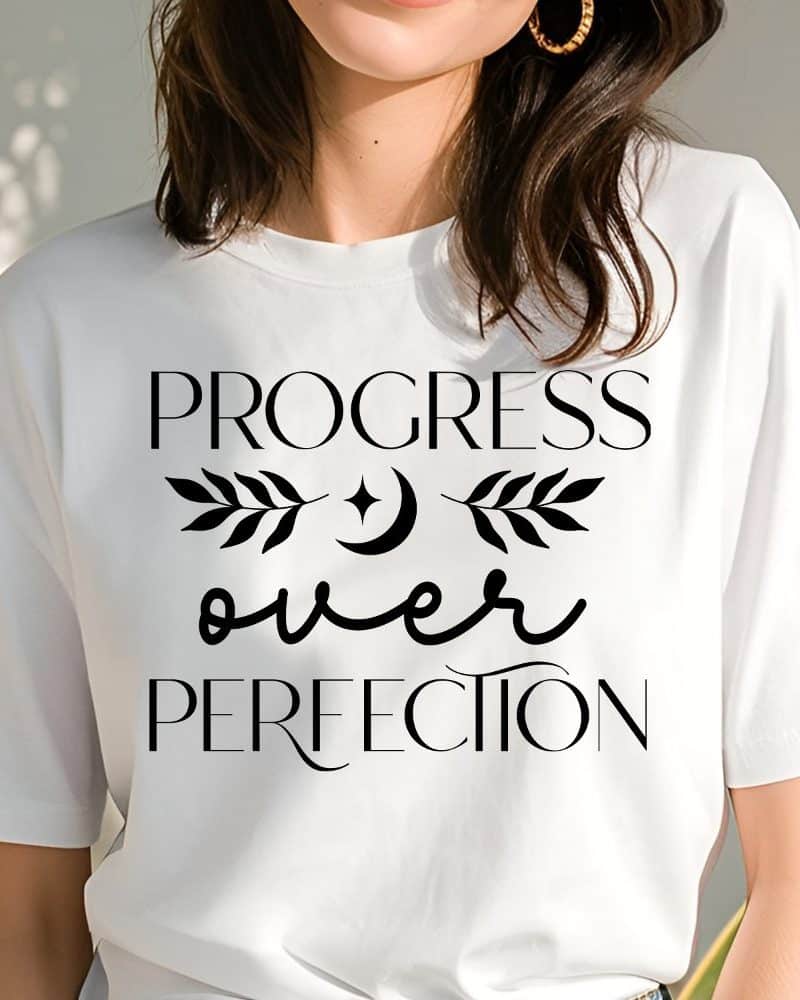 Woman wearing a white t-shirt with the text Progress over Perfection.