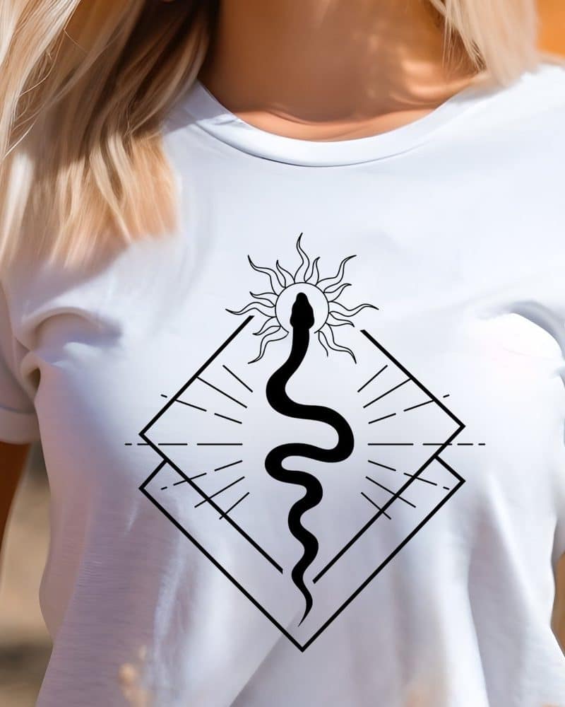 A woman wearing a white t-shirt with a graphic design of a snake rising from a sun within a geometric shape.
