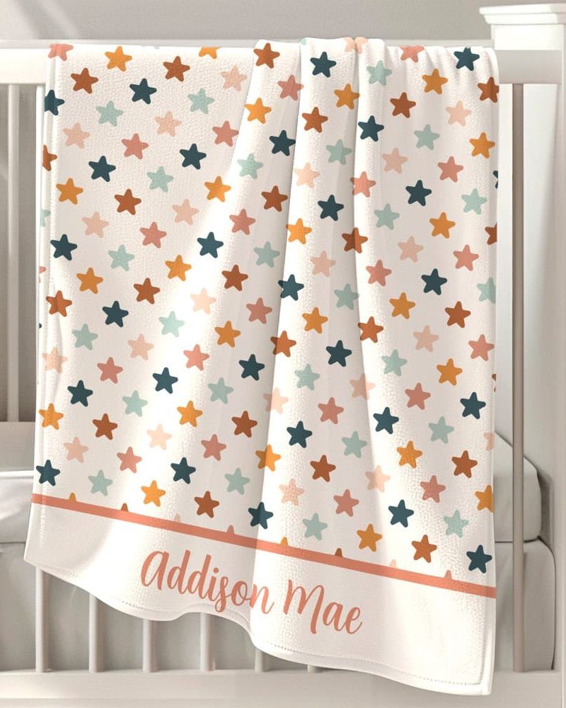 Personalized baby blanket with a star pattern in muted orange, pink, teal, and blue.