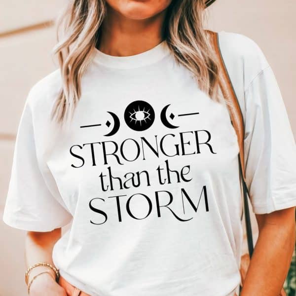 White T-Shirt With Black Text And Symbols That Reads Stronger Than The Storm.