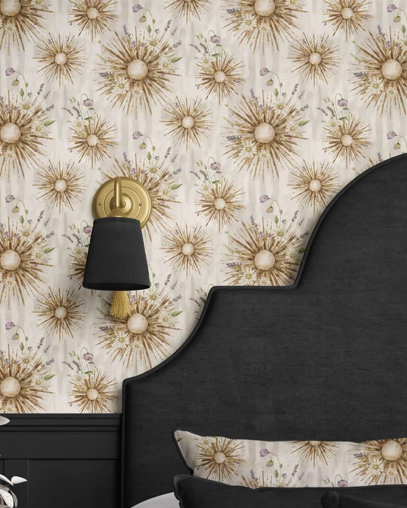 Beige wallpaper featuring a repeating pattern of sunbursts adorned with flowers and greenery, partially visible on a dark headboard.