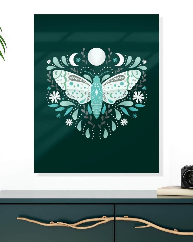 Teal and white moth illustration with floral accents and moons, on a dark green background.