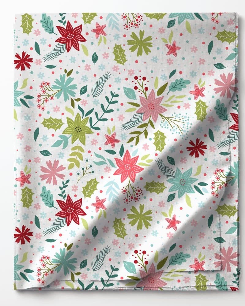 Folded fabric with a repeating pattern of red, pink, green, and blue flowers and leaves on a white background.