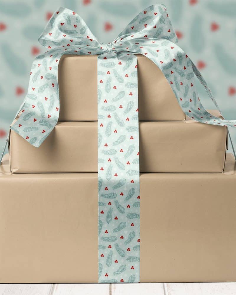 Three stacked presents tied with a teal ribbon featuring a wintery pattern.