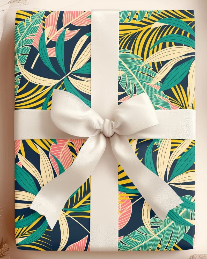 Gift box with tropical leaf pattern and white ribbon.