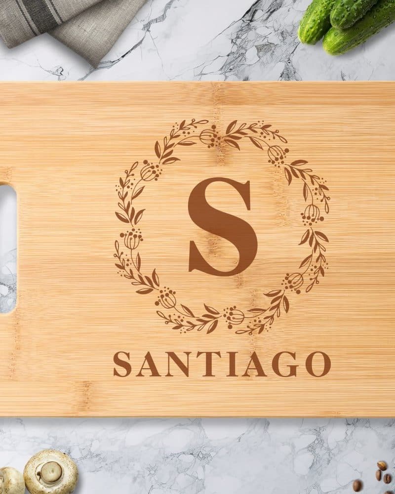 Personalized bamboo cutting board with the letter S in a floral wreath and the name Santiago.