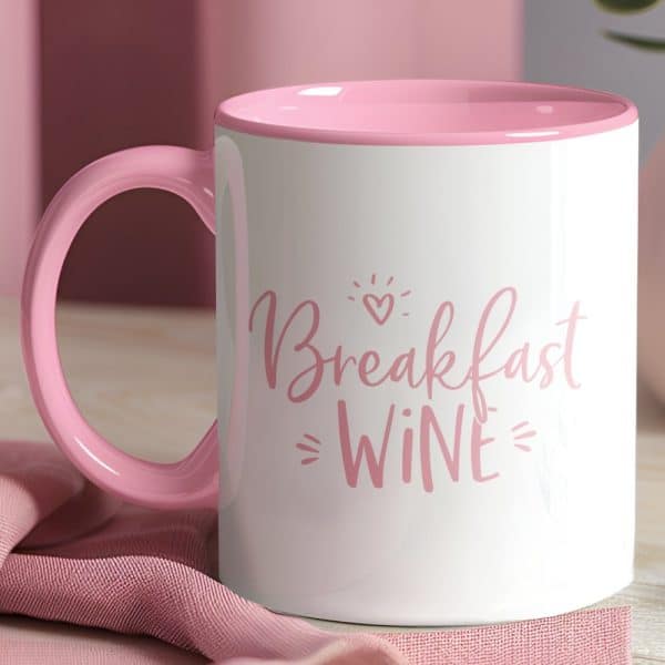 Pink Mug With The Phrase Breakfast Wine In Pink Lettering.