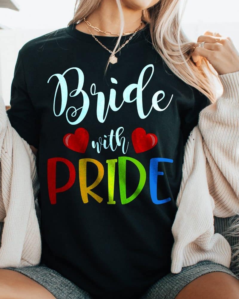 Woman wearing a black t-shirt that says Bride with Pride in rainbow letters.