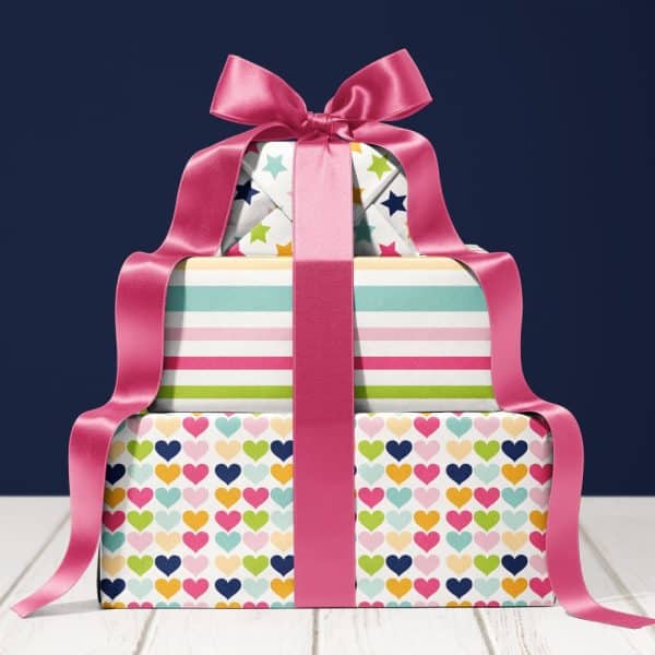 Stack Of Three Presents With Colorful Wrapping Paper And A Large Pink Ribbon.