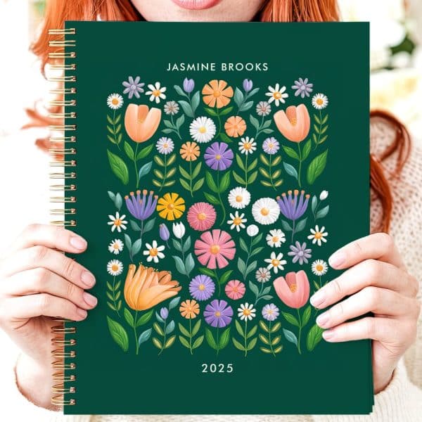 Person Holding A 2025 Planner With A Floral Design.