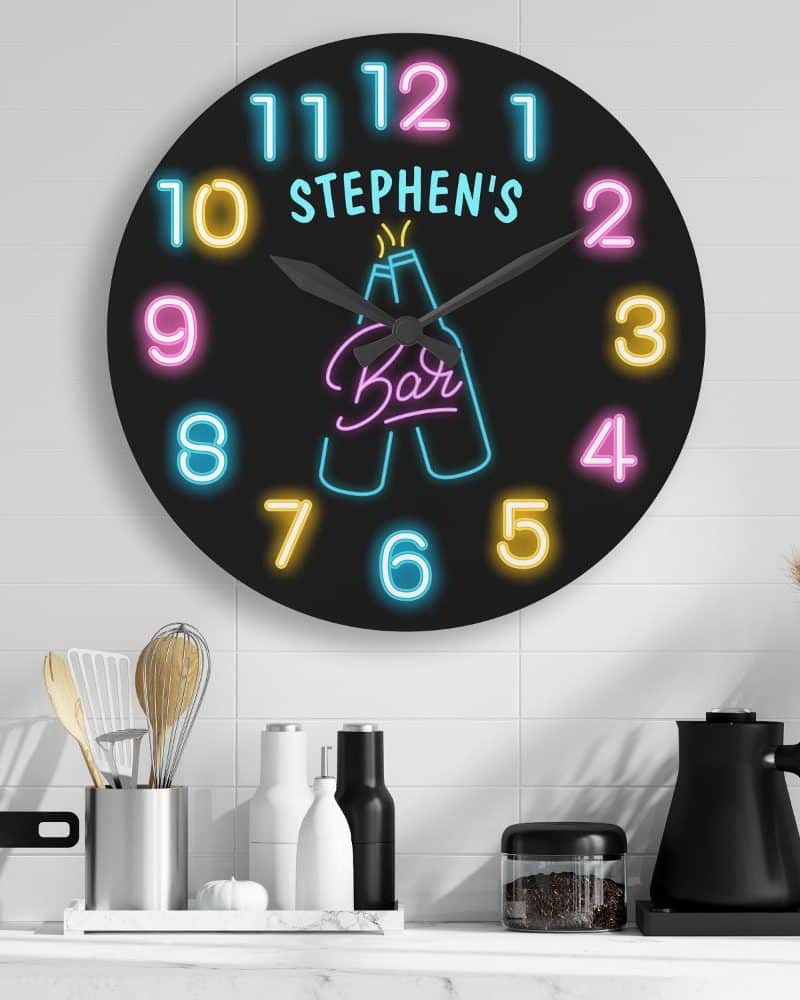 A round black clock with neon numbers and a neon bar design featuring two beer bottles. The clock is personalized with the name Stephen's.