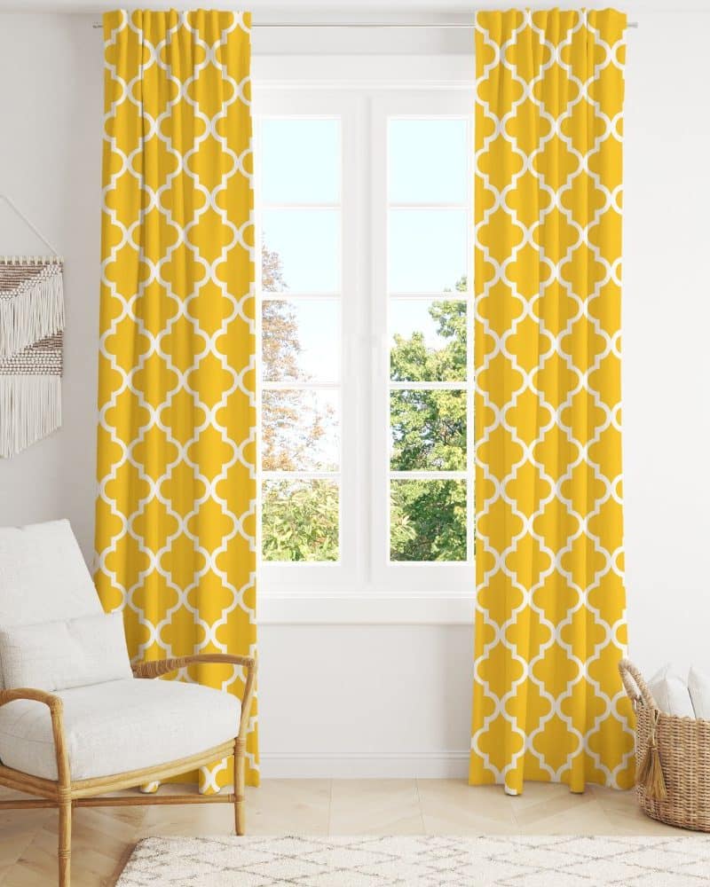 Mustard yellow curtains with a white quatrefoil pattern hang in front of a window.