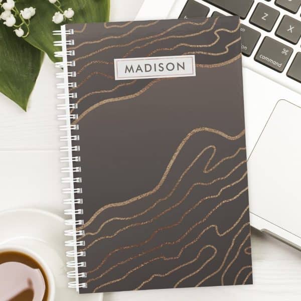 Spiral-Bound Notebook With Dark Gray Cover And Rose Gold Abstract Lines; The Name Madison Is Printed On The Cover.