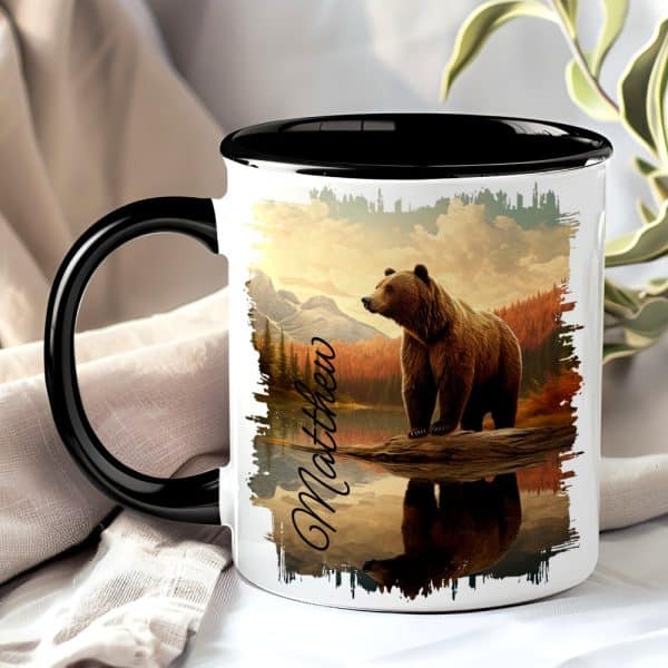 A Black-Handled Mug With A Grizzly Bear Image. The Bear Stands On A Log By A Lake, Mountains In The Background. The Name Matthew Is Printed On The Mug.