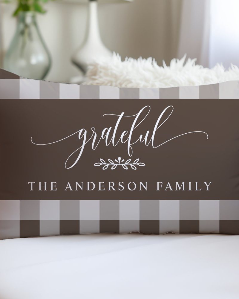 Brown and beige rectangular pillow with the word grateful in a script font, a small leaf design, and the text The Anderson Family.