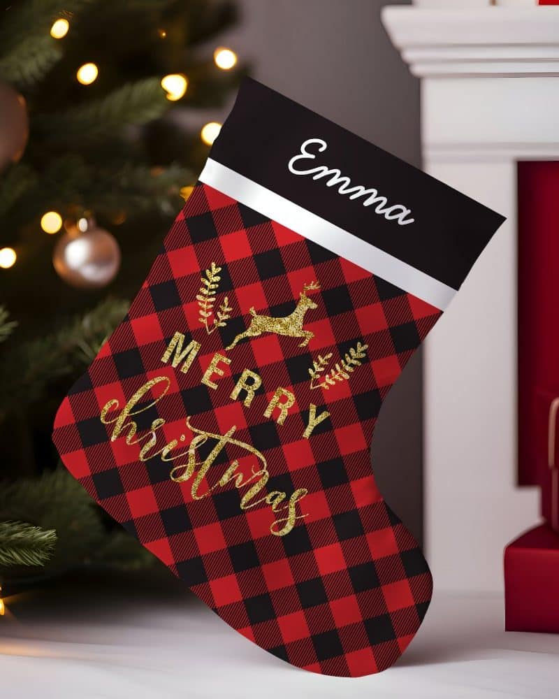 Red and black buffalo plaid Christmas stocking with gold lettering that says Merry Christmas and a gold reindeer. The stocking is personalized with the name Emma.