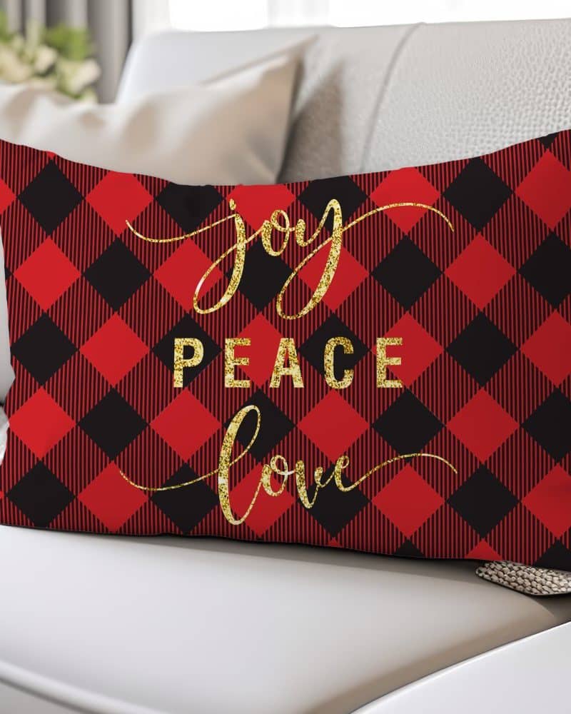 Red and black buffalo plaid rectangular pillow with gold glitter lettering spelling Joy Peace Love.