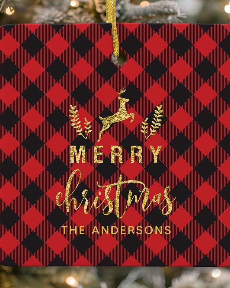 Red and black buffalo plaid Christmas ornament with a gold leaping reindeer and Merry Christmas text. The Andersons family name is also included.