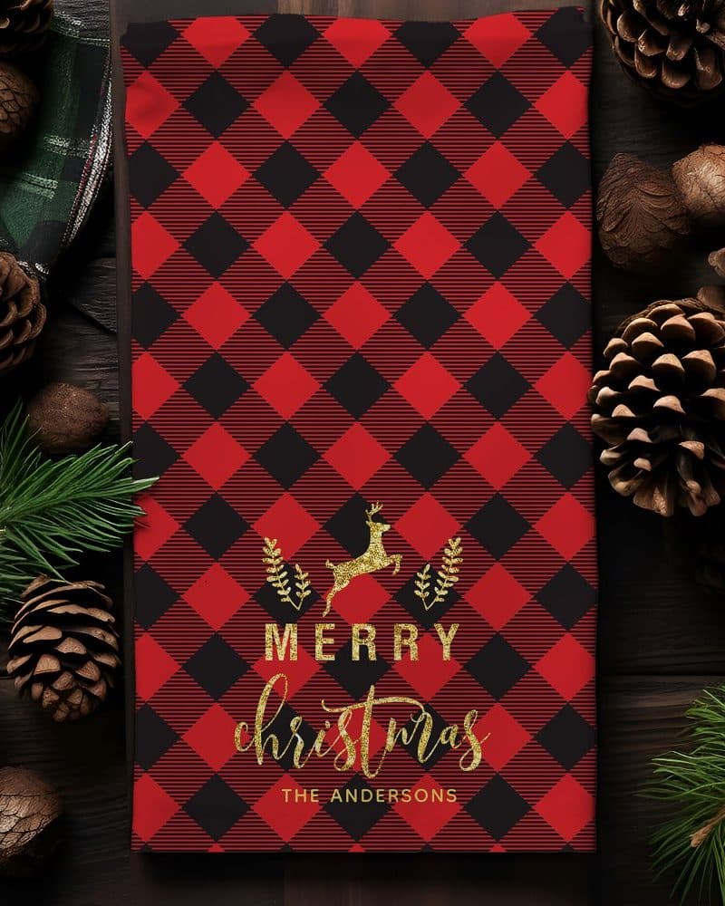 Red and black buffalo plaid Christmas towel with a gold reindeer and Merry Christmas text.