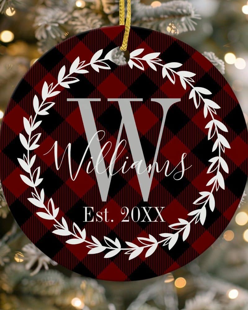 Round red and black buffalo plaid Christmas ornament with a large grey W, Williams, and Est. 20XX within a white wreath.