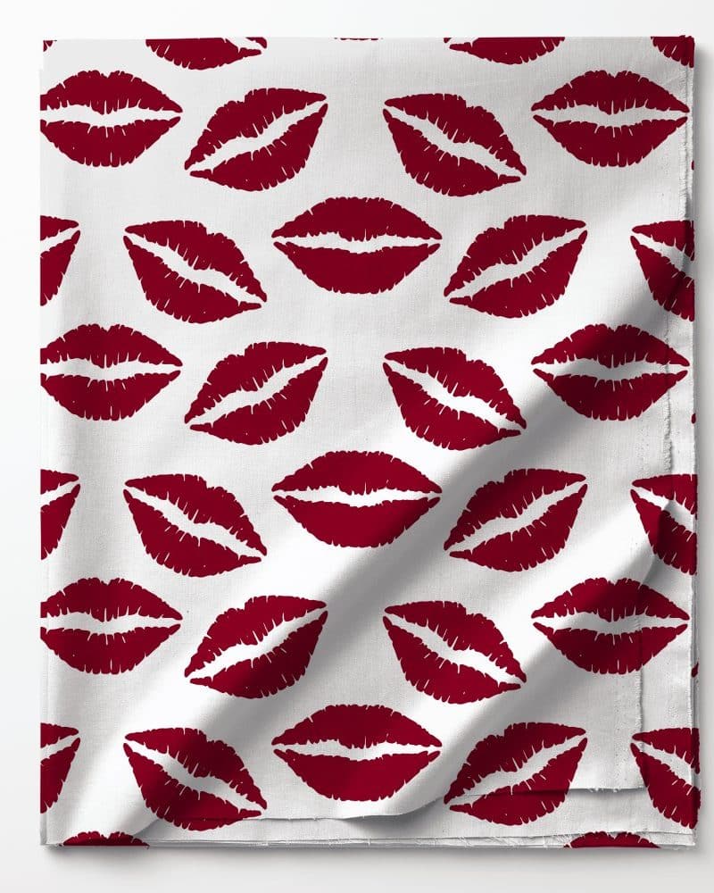 White fabric with a repeating pattern of dark red lipstick kisses.