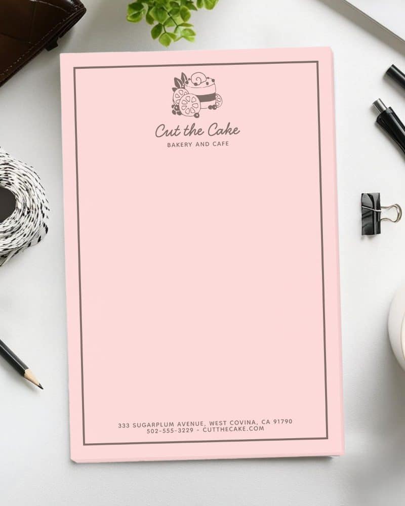 Pink stationery for Cut the Cake bakery and cafe. A logo of a cake is at the top. Contact information is at the bottom.