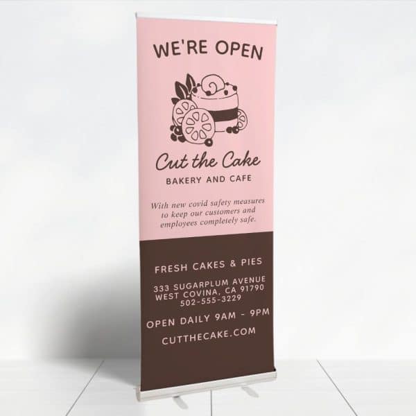 Retractible Banner For Cut The Cake Bakery And Cafe, Showing A Drawing Of A Cake And Announcing They Are Open.