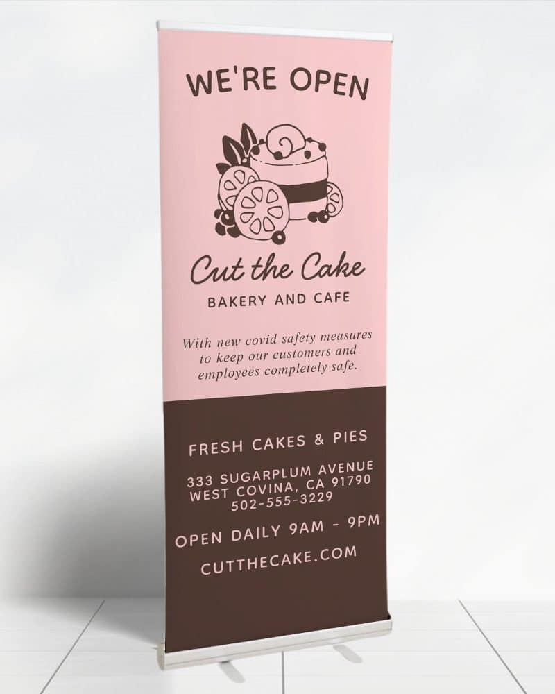 Retractible banner for Cut the Cake bakery and cafe, showing a drawing of a cake and announcing they are open.
