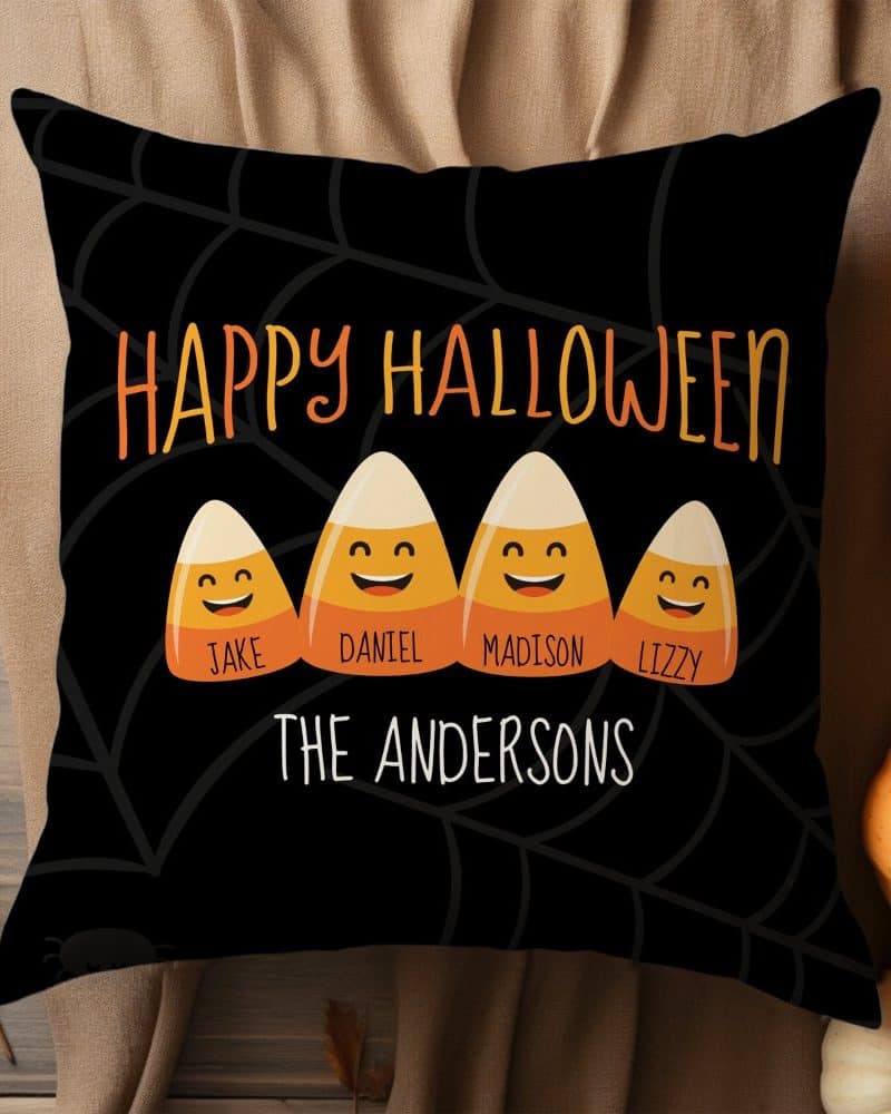Black Halloween pillow with four smiling candy corn characters, each labeled with a name, and the family name, The Andersons, below.