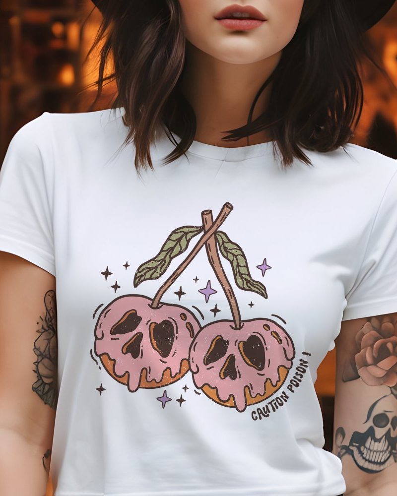 Woman wearing a white t-shirt featuring a graphic of two pink cherries with skull-like designs and the text Caution Poison.